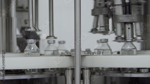 glass bottles filled and sealed with rubber caps on a medical solution conveyor line aluminium cap packaging section selective focus medical industry