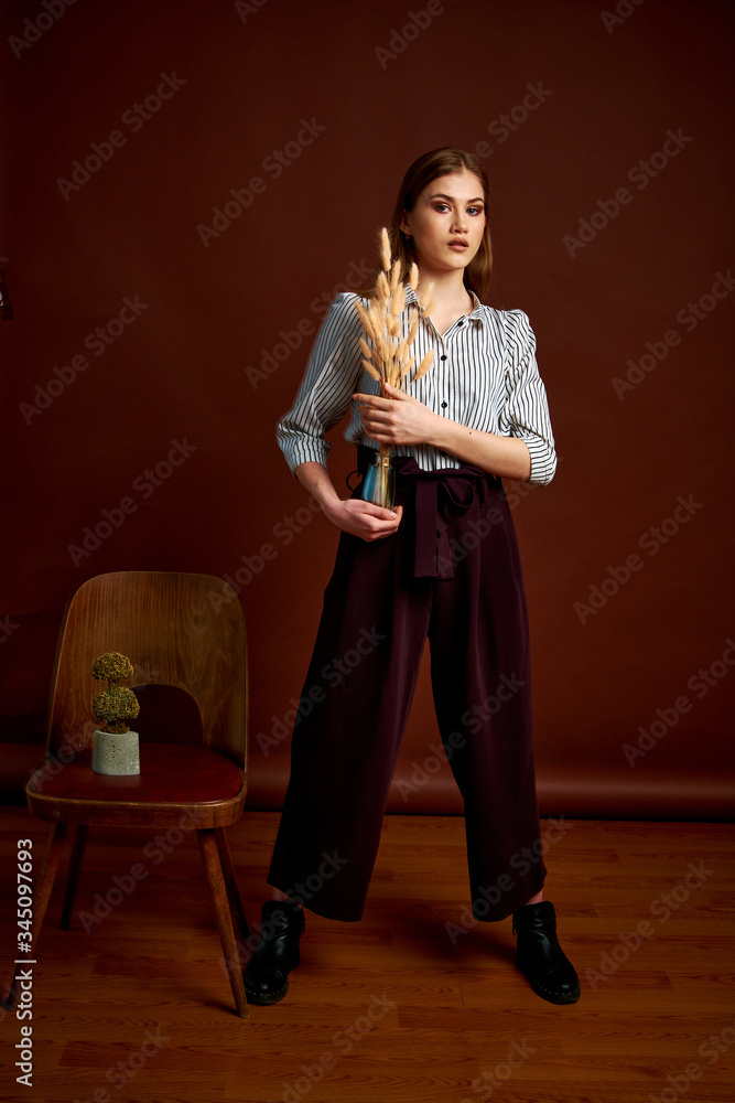 Fototapeta premium Gorgeous young female in classic suit, black shoes and grey coat. Vintage chair. Woman's clothes.