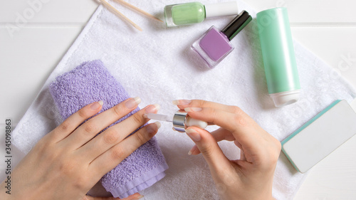Manicure. A woman applies a moisturizer to the cuticle. Manicure tools  nail polishes  oil. Home nail care  SPA  beauty. Long natural nails. Beauty salon.