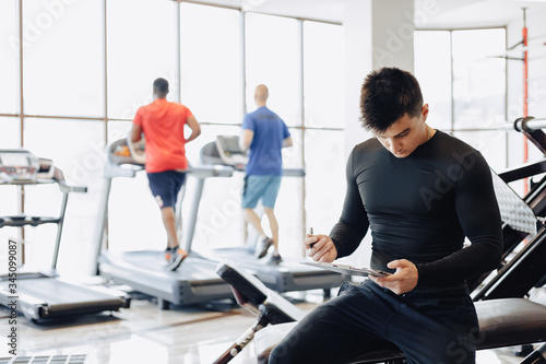 young guy trainer takes notes in the gym. personal trainer for sports.