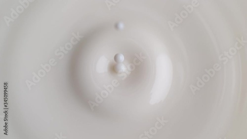 Milk Drop Dripping onto the White Liquid Surface Making Crown and Circular Ripples