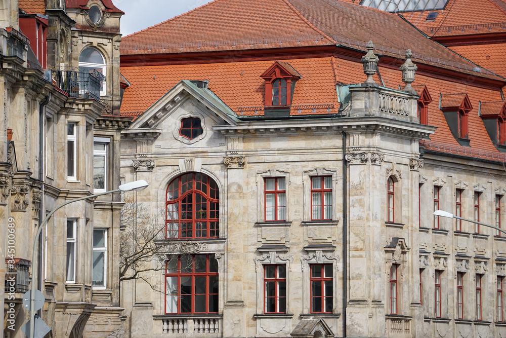 Obraz premium Fassade eines klassischen Gebäudes mit Sandstein, roten Fenstern mit Bogen und roten Dachziegeln. Amtsgericht Bayreuth von Hinten. Bayern, Deutschland.