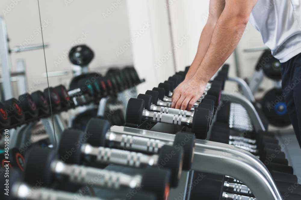 Sporty young man training with dumbbells in gym Sporty young man training with dumbbells in gym