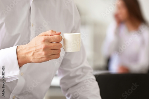 Young man drinking coffee in office, closeup