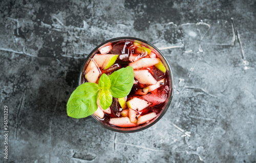 Old fashioned cocktail with blackberry liqueur and apple slices on rustic background. Selective focus. Shallow depth of field.
