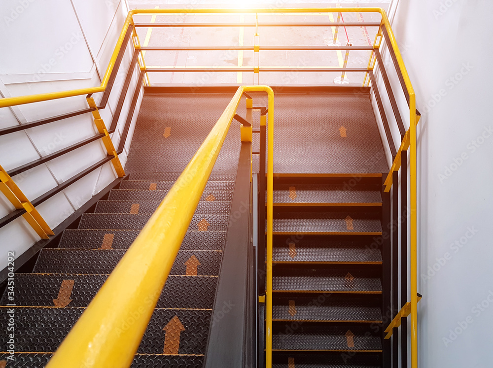The walkway shows safe climbing using the yellow arrows to indicate walking direction and soft light, Fire escape stairs, Steel stairs and rails, The staircase clearly indicates the pathway The walkway shows safe climbing using the yellow arrows to indicate walking direction and soft light, Fire escape stairs, Steel stairs and rails, The staircase clearly indicates the pathway
