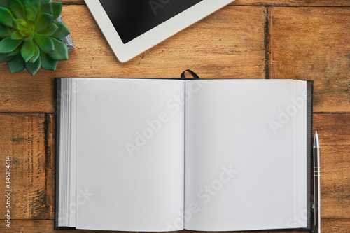 Blank open notebook with tablet wooden table, desktop. Top view image.