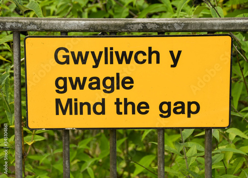 Close up view of a bilingual  Mind the Gap  sign on a railway station platform