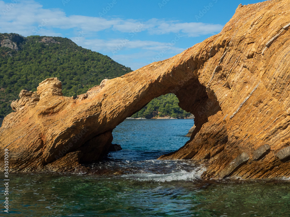 View of the coast from the sea. Rock arch. Bright sunny summer day.