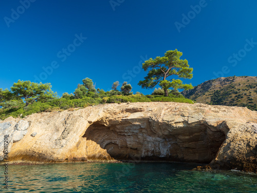 View of the coast from the sea. Amazing color of water, beautiful rocks with trees growing on them. Bright sunny summer day.