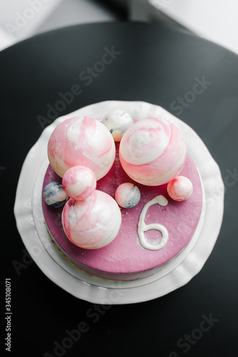 purple cake with chocolate balls of different sizes and the number six