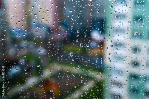 Raindrops on window glass. Selective focus. Rainy city background © Vadim