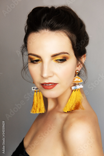 Beautiful girl with yellow makeu-up and earrings