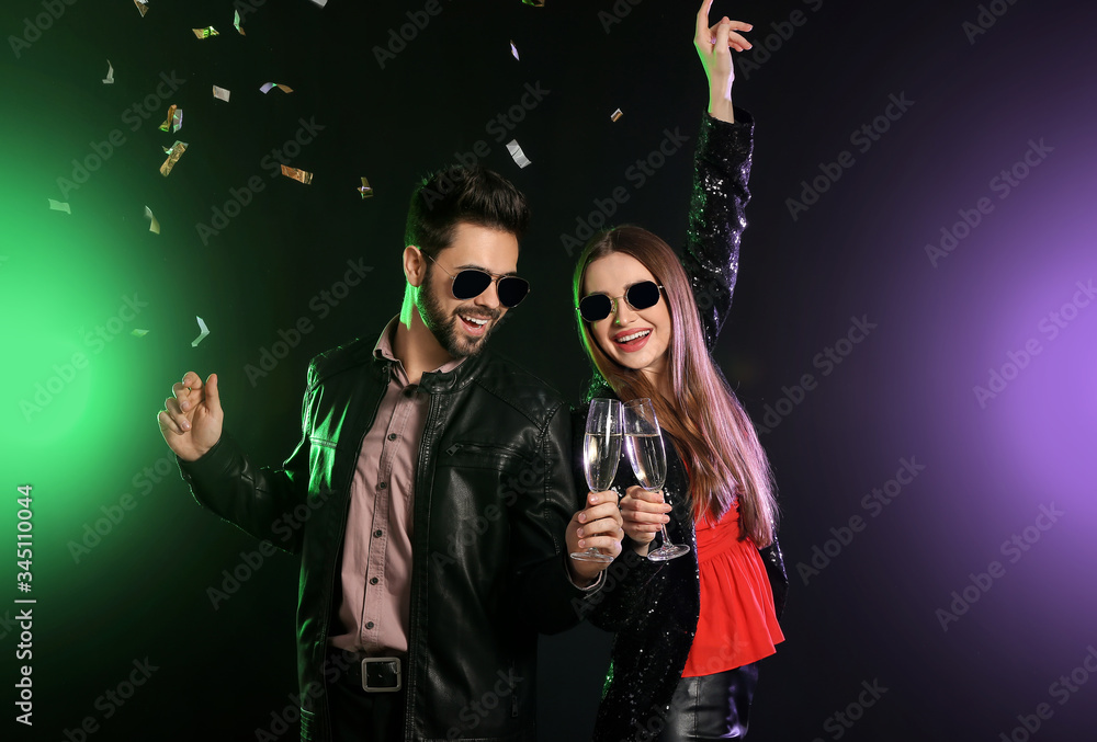 Happy couple with glasses of champagne on dark background