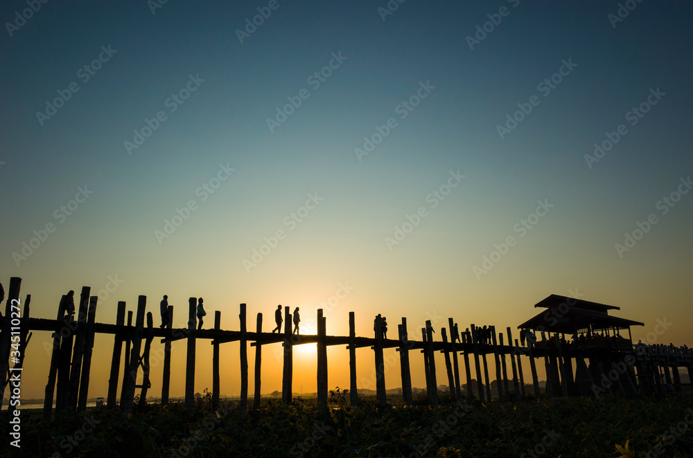 Obraz premium Silhouette of U bein bridge at sunset with sunrays shining under bridge in Amarapura, Mandalay, Myanmar