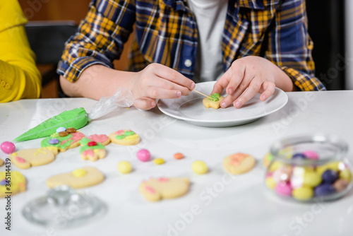Children decorating cookies with sugar icing for holidays
