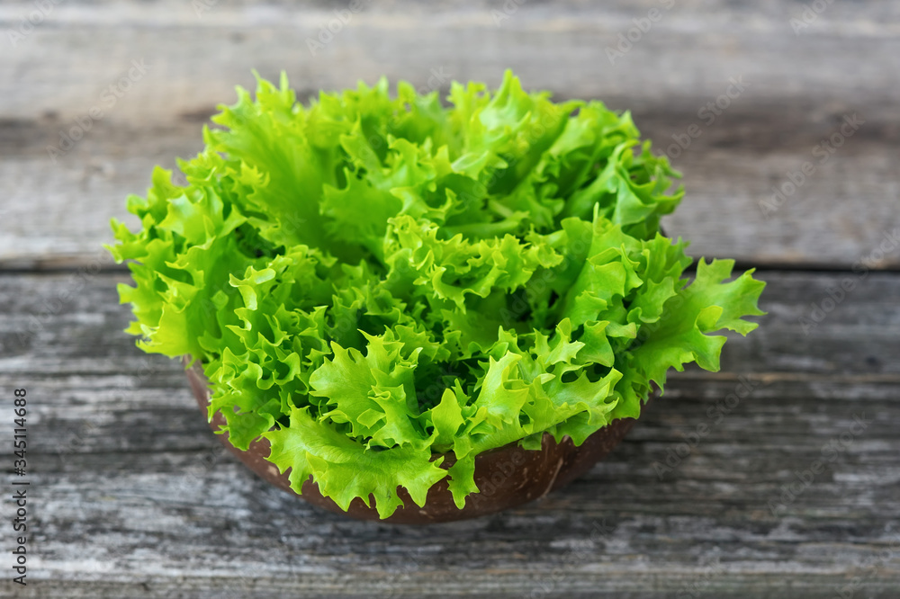Fresh lettuce leaves in a bowl on rustic wooden background Fresh lettuce leaves in a bowl on rustic wooden background