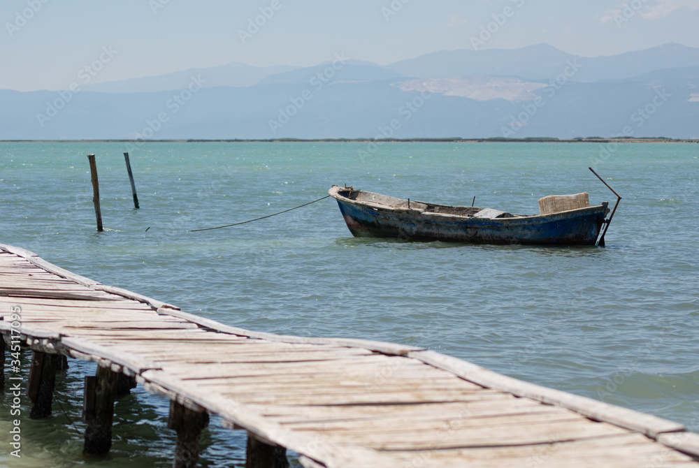 An old wooden boat by a wooden pier at a sea