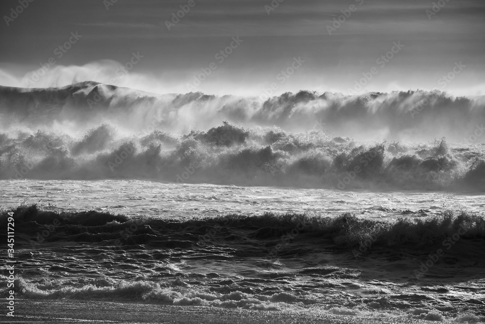 Black and white image of big waves from portuguese beach `Praia Norte` in Nazare. Scenic, danger.