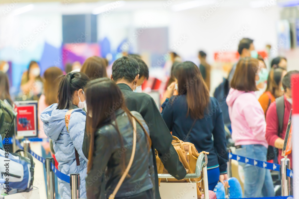 Crowd of people with luggage waiting in line in airport during coronavirus quarantine