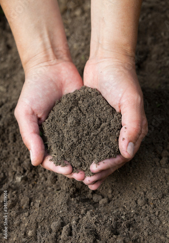 Hands holding black soil. Close-up.