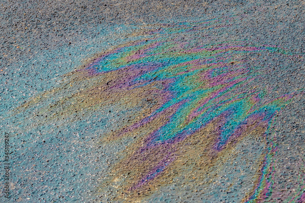 Fuel spill on a ground. Petroleum pollution is toxic for environment. Bright colors from oil spill on asphalt.