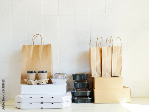 many others paper packages and containers for takeaway food on desk wiht white background. Takeout meal, deivery to home, food delivery, online shopping concept. photo