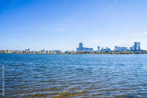 Beautiful urban lake with buildings and skyscrapers on the horizon © Payllik