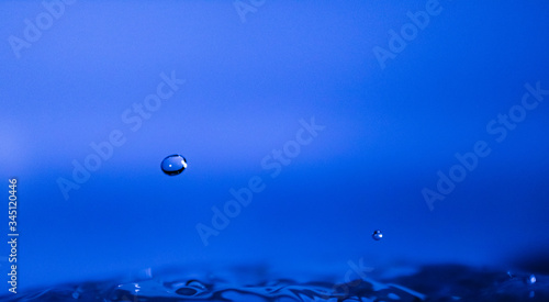 Water drop creating waves ripples and air borne water droplet