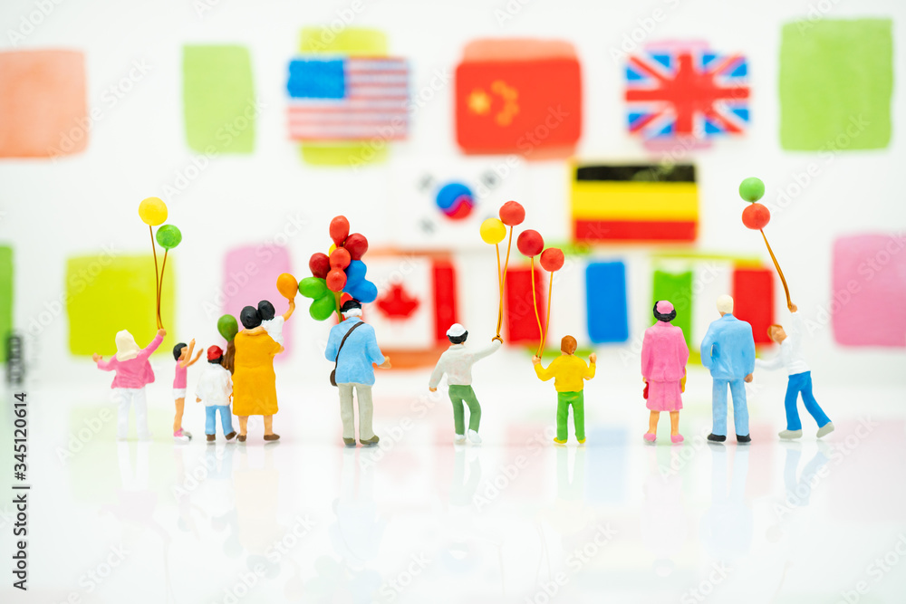 Miniature people: Back view of happy family holding balloons and international flag with copy space using as background international family day, happy, love concept.