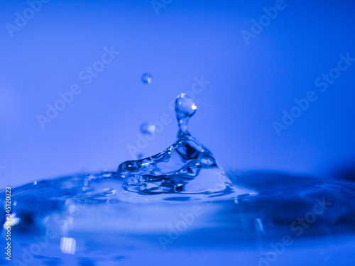 Water drop creating waves ripples and air borne water droplet