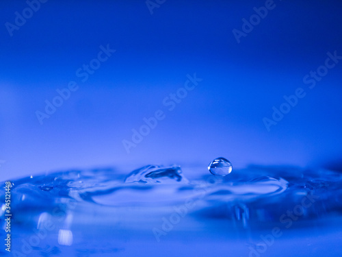 Water drop creating waves ripples and air borne water droplet