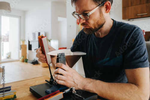 caucasian man sharpening a kitchen knife with a modern whetstone device photo