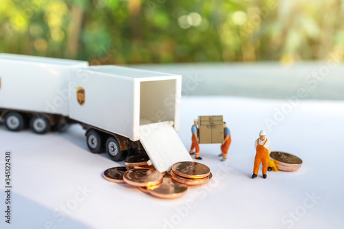 Miniature people:  Worker loading box and coins  to truck container. Shipping and online delivery service concept.