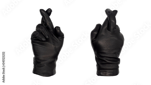 Hands wearing black leather gloves make the fingers crossed gesture, view from front and back. Female hand isolated, no skin