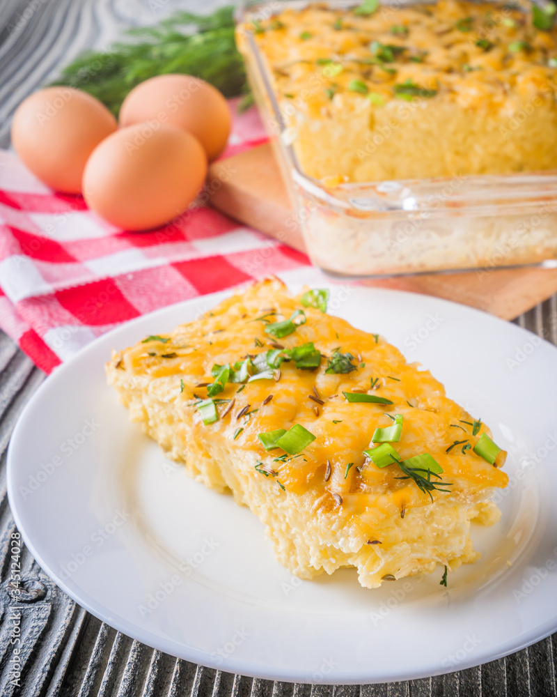 Delicious potato casserole with egg and cheese on a gray wooden background Delicious potato casserole with egg and cheese on a gray wooden background