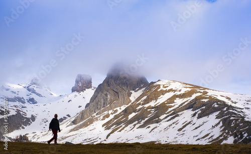 Hiker in the port of Aisa with Mallos de Lecherin and Pico Riguelo snowy, Huesca, Spain
