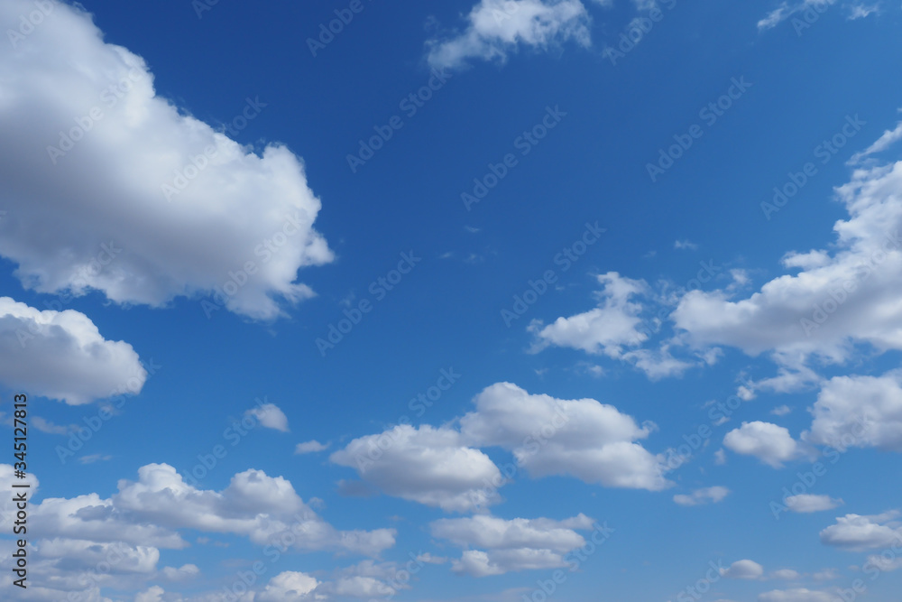 White fluffy clouds on a blue sky. Background. Wallpaper.