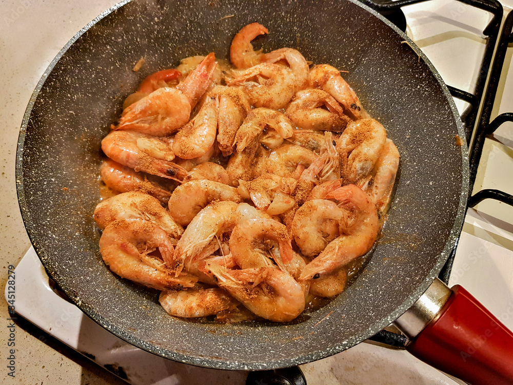 Giant orange shrimps fried in oil in a frying pan on a gas stove Giant orange shrimps fried in oil in a frying pan on a gas stove