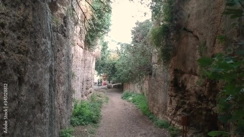 backwards flight through the path between high stone walls to titus vespasianus tunnel which is the first hand made tunnel in the world