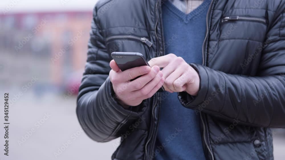 A man works on a smartphone - front closeup - suburban area in the blurry background A man works on a smartphone - front closeup - suburban area in the blurry background