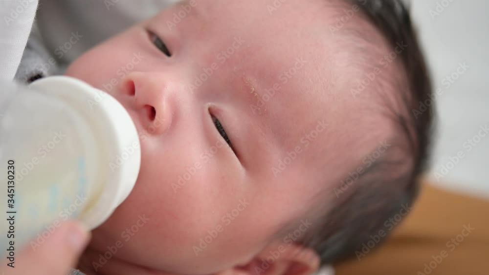 Mother feeding her adorable newborn baby kid's room at home.A woman feeds a newborn with modified milk from a bottle Mother feeding her adorable newborn baby kid's room at home.A woman feeds a newborn with modified milk from a bottle
