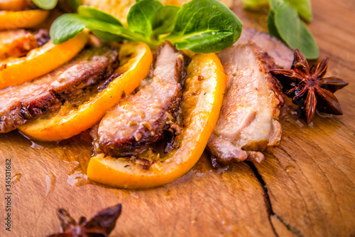 Juicy stewed duck breast in the company of turmeric with prunes, dried apricots and orange sauce on a wooden board