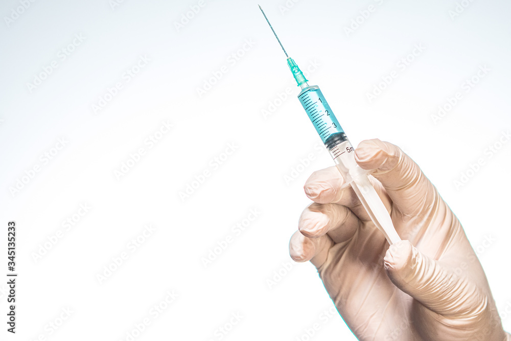 Hand wearing latex glove holding syringe with a medicine on white background Hand wearing latex glove holding syringe with a medicine on white background