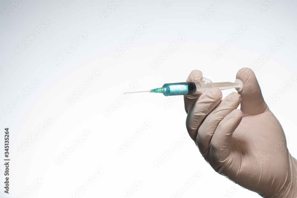 Hand wearing latex glove holding syringe with a medicine on white background Hand wearing latex glove holding syringe with a medicine on white background