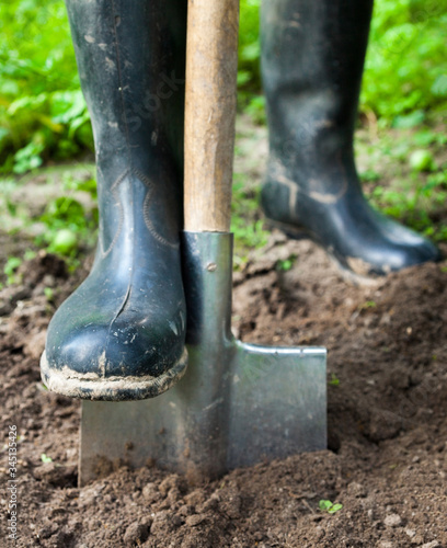 Foot in rubber boot on the metal spade