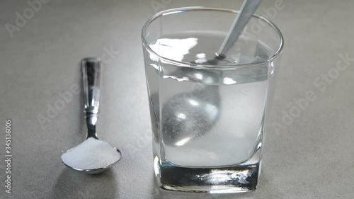 Preparing salt water by stirring salt and water. Salt water has high level of minerals and salt water gargle helps in removing of cold and sore throat. 