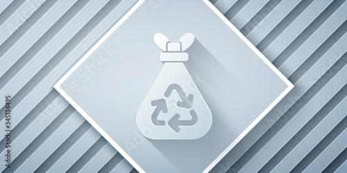 Paper cut Garbage bag with recycle symbol icon isolated on grey background. Trash can icon. Recycle basket sign. Paper art style. Vector Illustration