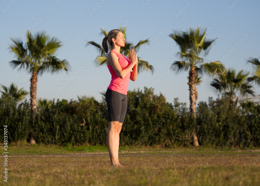 Greeting to the sun. Adult caucasian woman fold her hands in namaste gesture and ready to practice yoga outdoor in summer, selective focus. Greeting to the sun. Adult caucasian woman fold her hands in namaste gesture and ready to practice yoga outdoor in summer, selective focus.