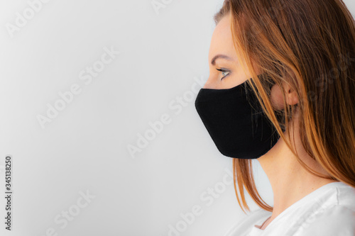 Profile of a young woman in a black medical mask and white t-shirt on a light background. Quarantine of coronavirus epidemic just ended, covid-19. Stay home concept. Virus protection. New realit. photo
